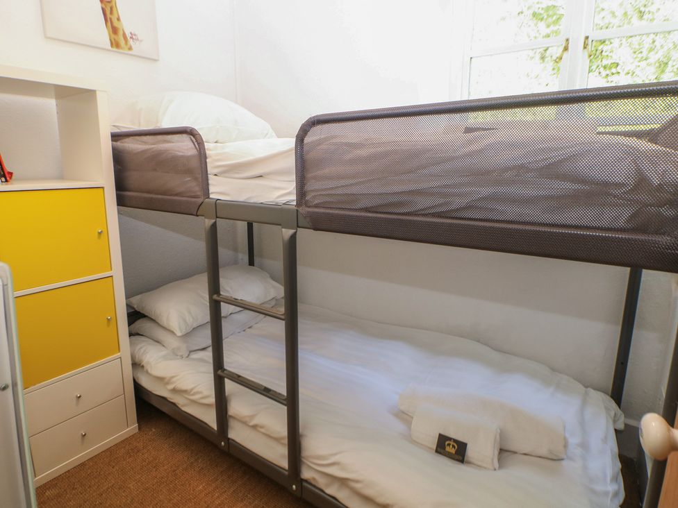 A bunk bed with linens in a bedroom at Honeysuckle Cottage