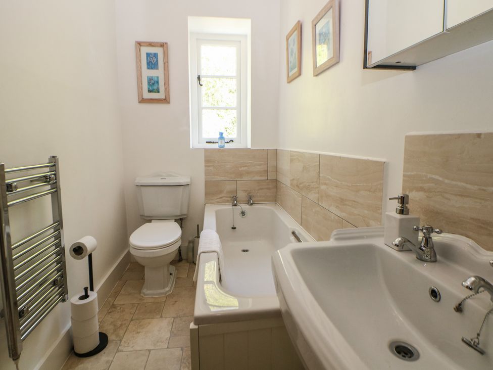 A bathroom with a bathtub, toilet and sink at Honeysuckle Cottage