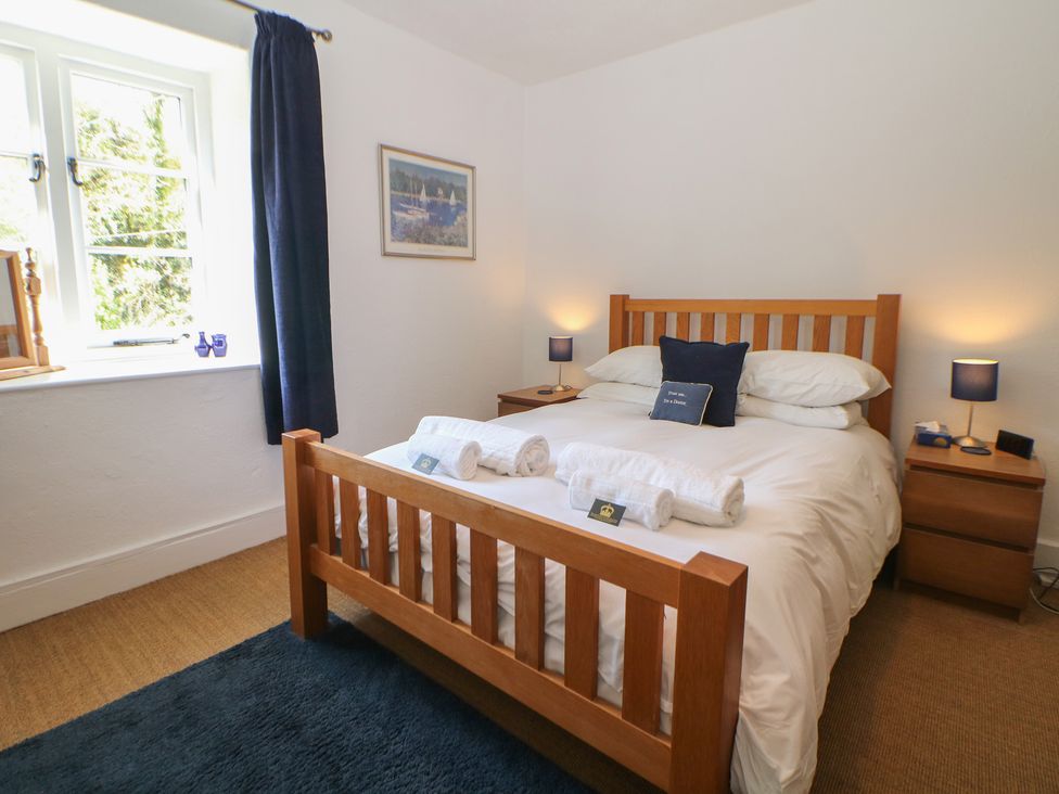 A bedroom with a double bed and two nightstands at Honeysuckle Cottage