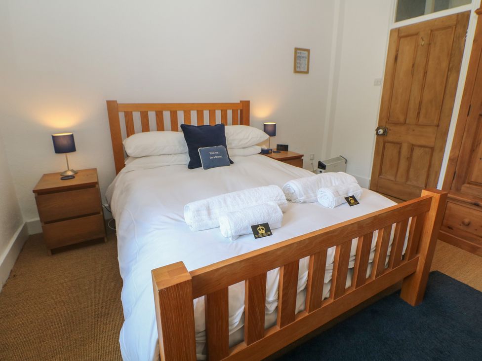A bedroom with a wooden bed and nightstand at Honeysuckle Cottage