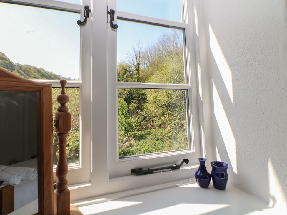 A window with a view and a vase on the sill at Honeysuckle Cottage