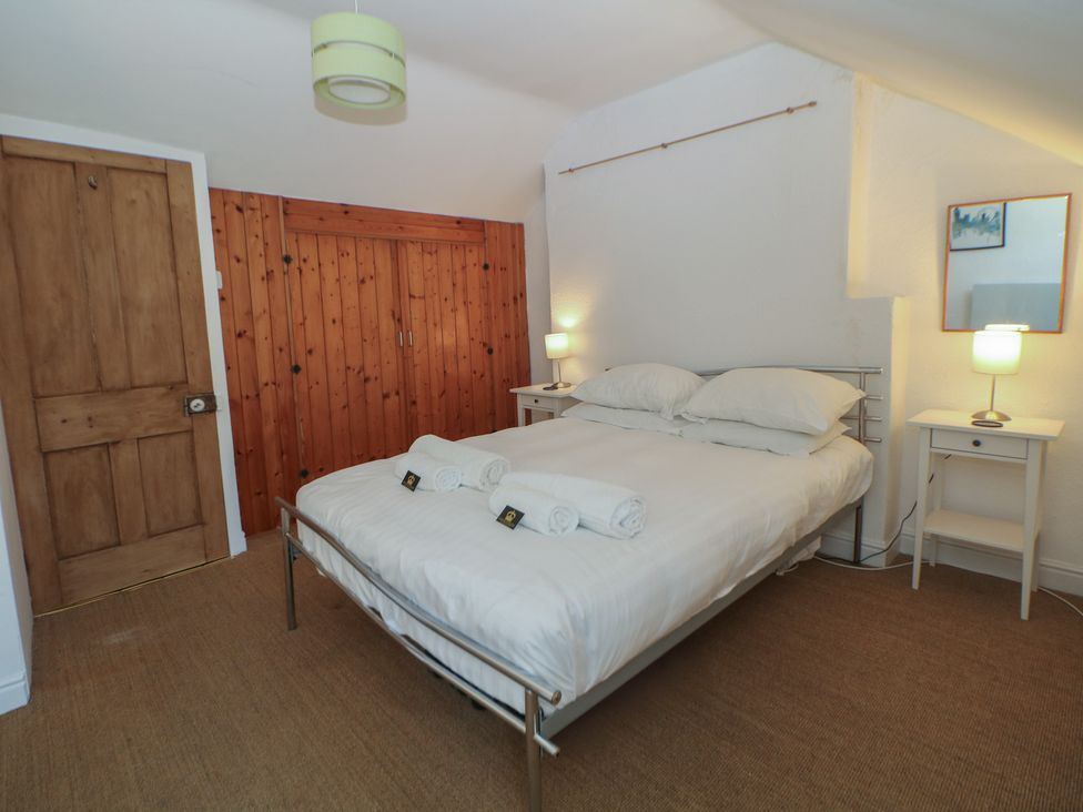 A bedroom with a bed and bedside tables at Honeysuckle Cottage