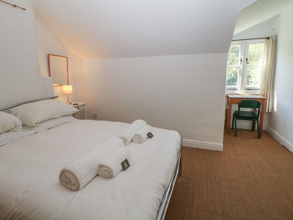 A bedroom with a bed and a desk at Honeysuckle Cottage