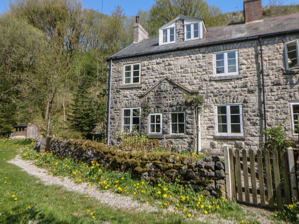 A stone house with windows and a pathway at Honeysuckle Cottage