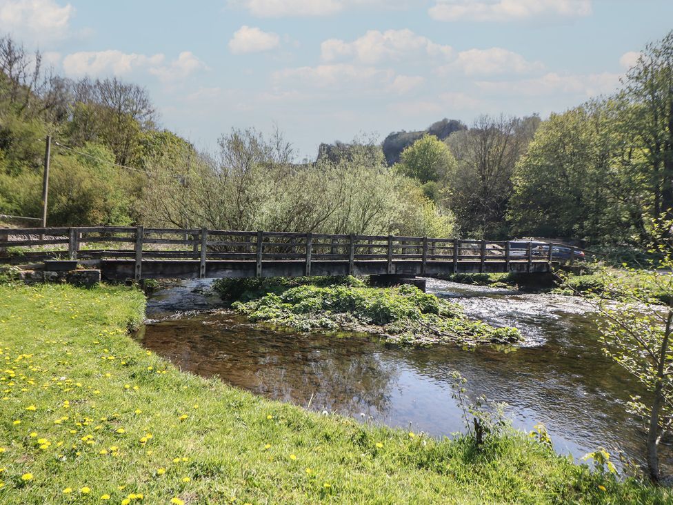 A bridge over a river with greenery at Honeysuckle Cottage