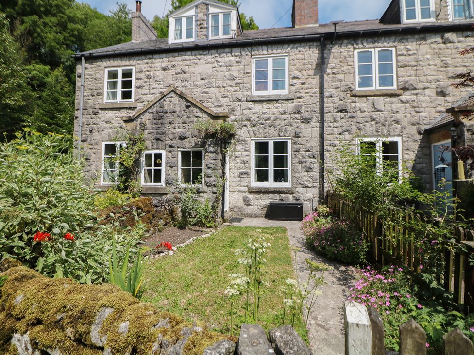 A stone house with a garden and pathway at Honeysuckle Cottage near Blackwell Mill Buxton
