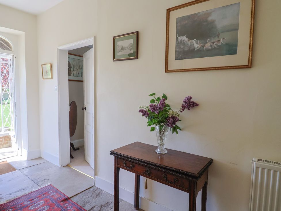 A hallway with a table and vase of flowers at Goulds Farmhouse, Milborne St Andrew
