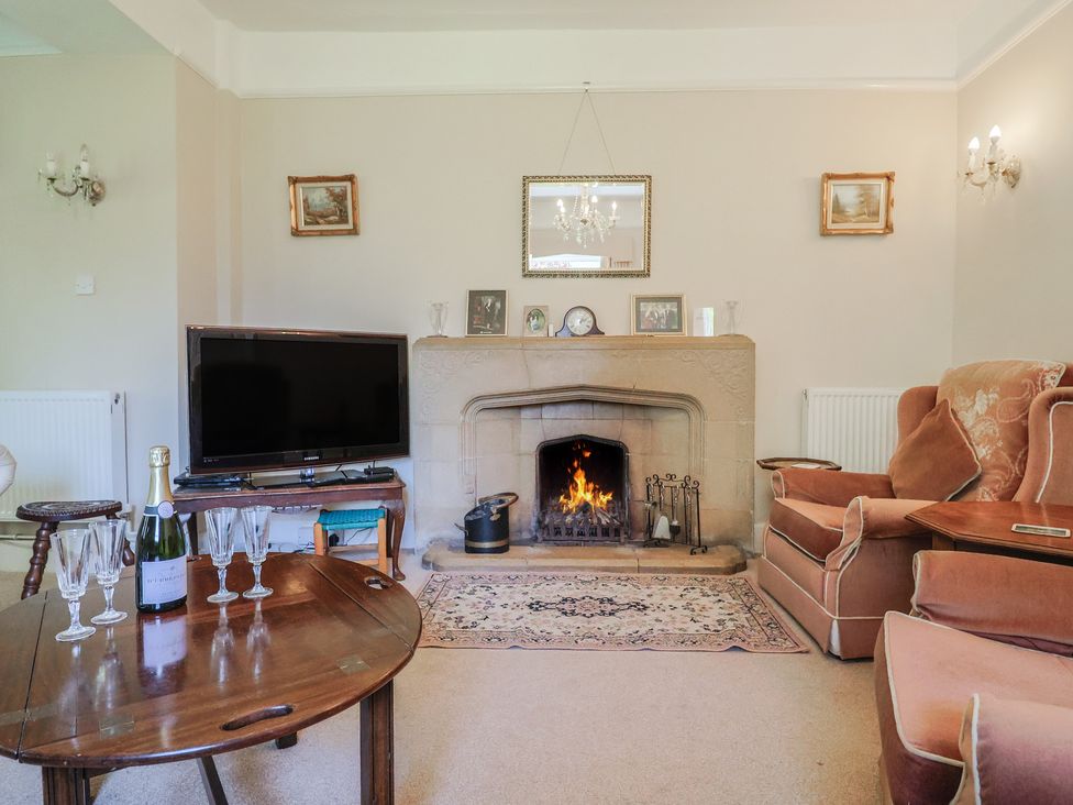 A living room with a fireplace and television at Goulds Farmhouse in Milborne St Andrew