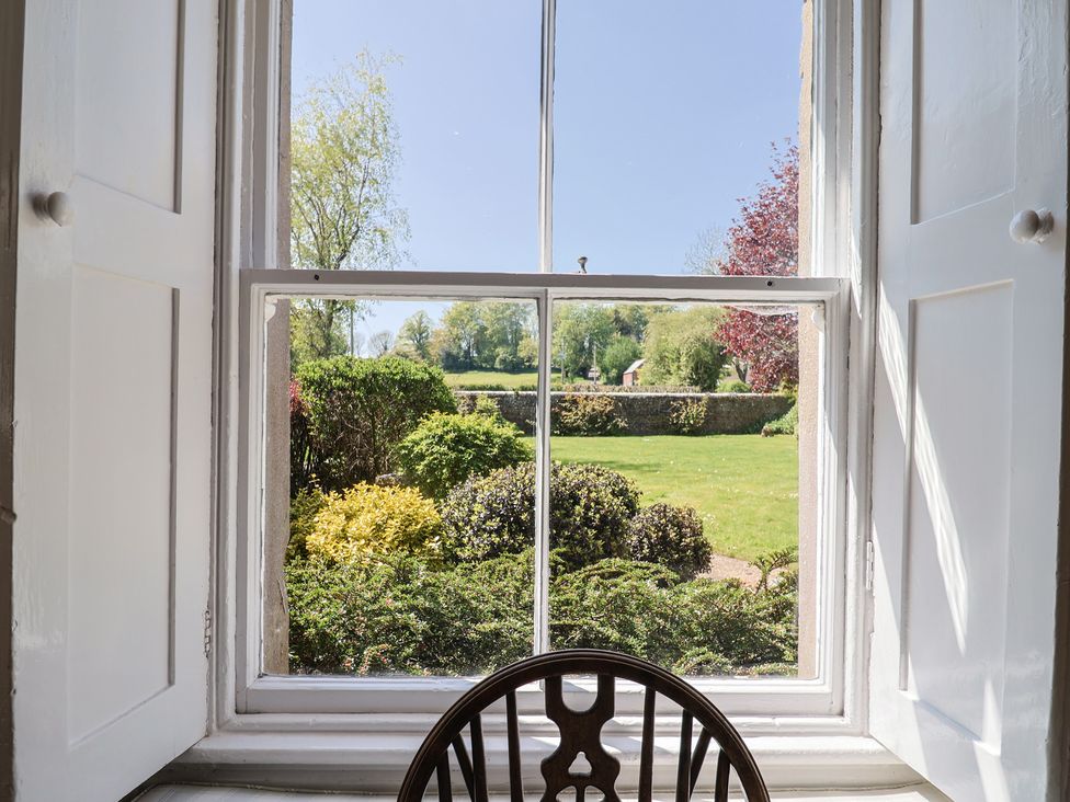 A window view of a garden with grass and bushes at Goulds Farmhouse in Milborne St Andrew