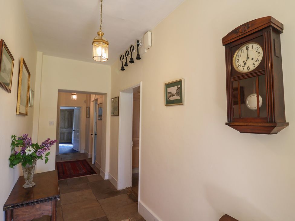 A hallway with a clock and decorative wall art at Goulds Farmhouse in Milborne St Andrew