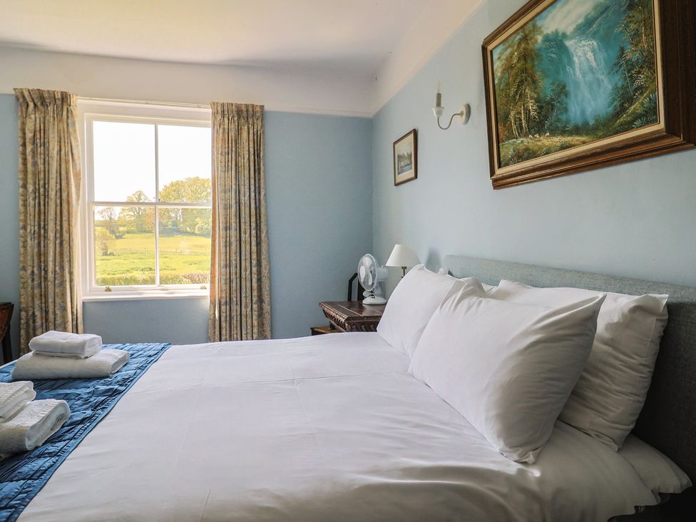 A bedroom with a bed, window, and fan at Goulds Farmhouse in Milborne St Andrew