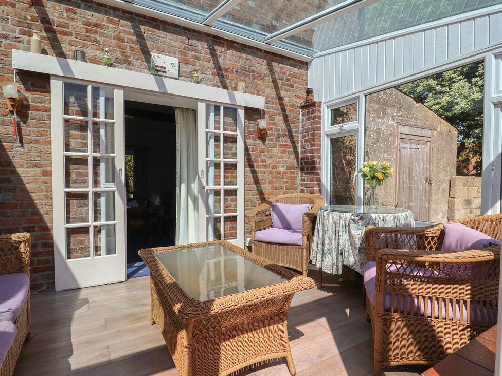 A conservatory with wicker furniture and a glass table at Goulds Farmhouse in Milborne St Andrew