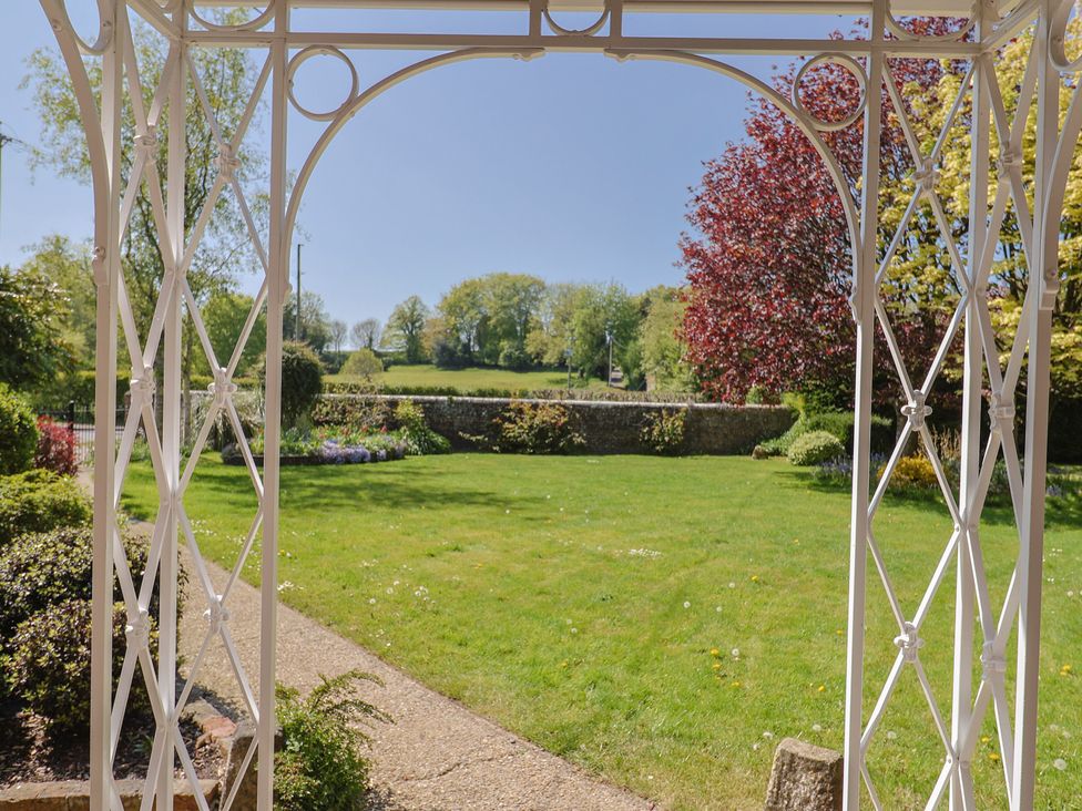 A garden with a view through a gazebo at Goulds Farmhouse in Milborne St Andrew