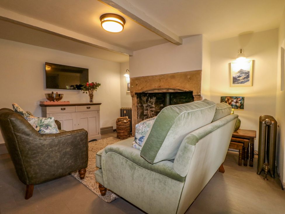 A living room with a sofa and fireplace at Hope Cottage in Great Longstone