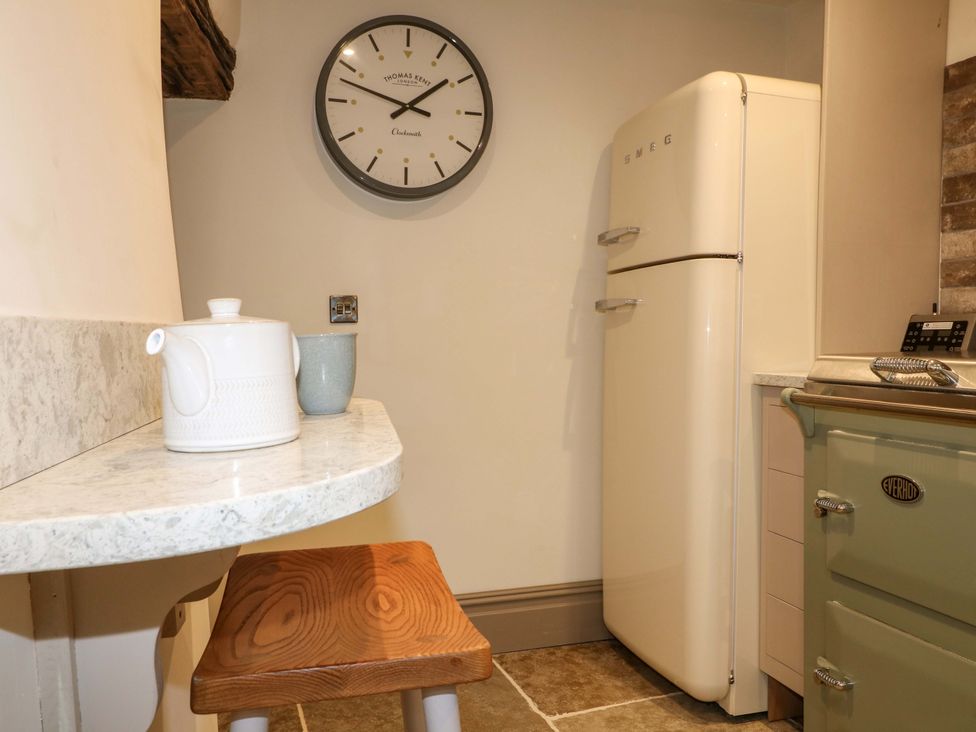 A kitchen with a kettle, cup, and refrigerator at Hope Cottage in Great Longstone