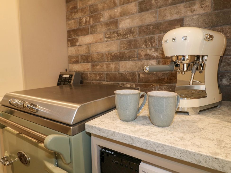A kitchen with an espresso machine and mugs at Hope Cottage in Great Longstone