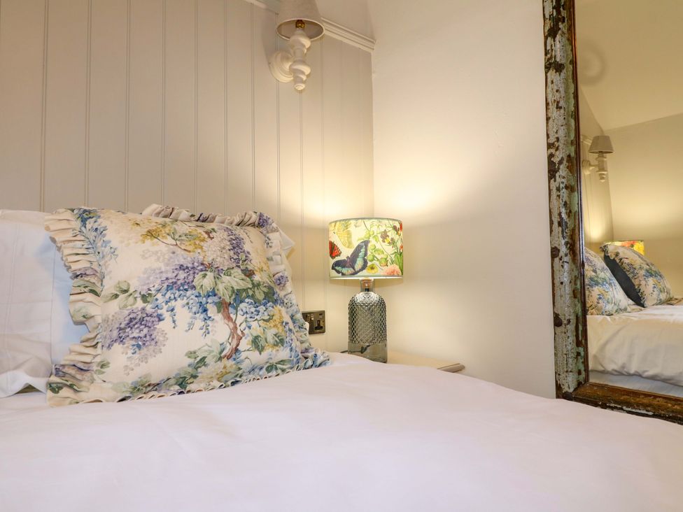 A bedroom with a bed, lamp, and mirror at Hope Cottage in Great Longstone