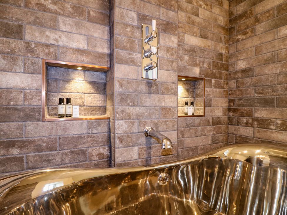 A bathtub and shower controls in a bathroom at Hope Cottage in Great Longstone