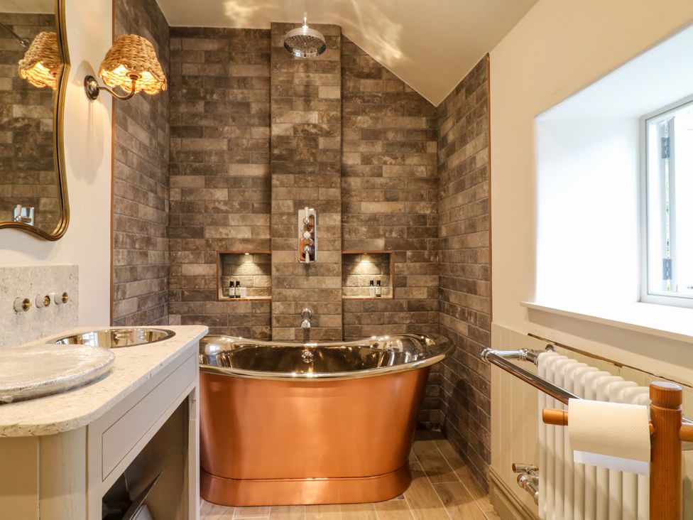 A bathroom with a copper bathtub and sink at Hope Cottage in Great Longstone
