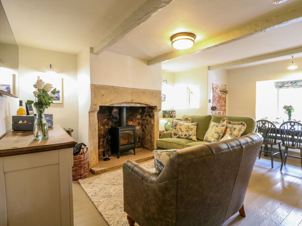A living room with a sofa, fireplace, and dining area at Hope Cottage in Great Longstone
