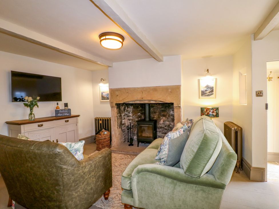 A living room with a fireplace and TV at Hope Cottage in Great Longstone