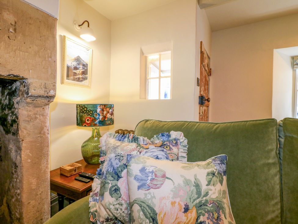A living room with a sofa, lamp, and decorative pillows at Hope Cottage in Great Longstone