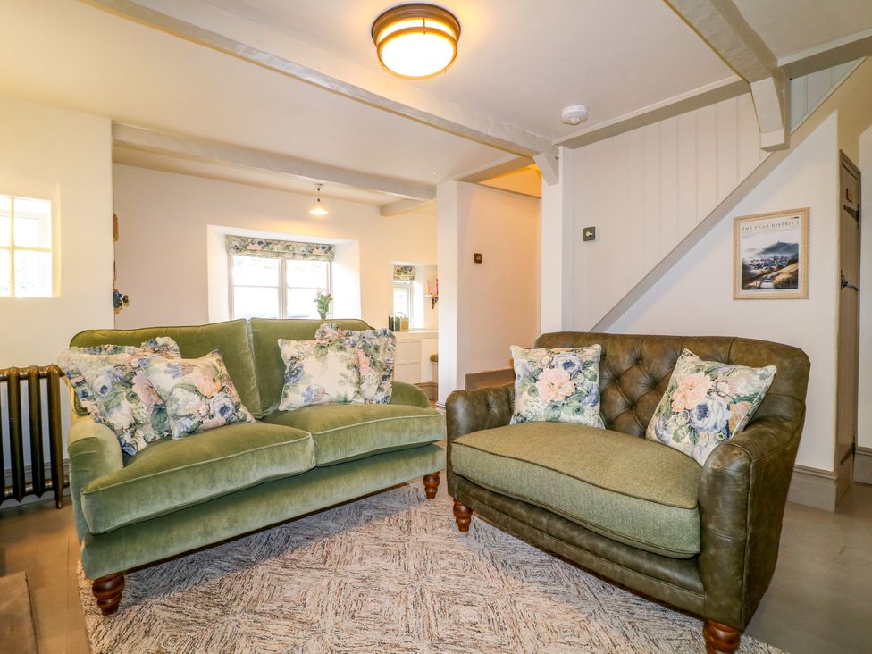 A living room with a green sofa and armchair at Hope Cottage in Great Longstone