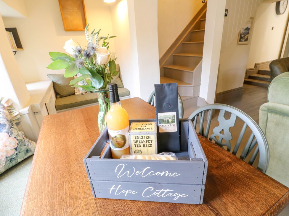 A dining room with a wooden table and a welcome box at Hope Cottage in Great Longstone