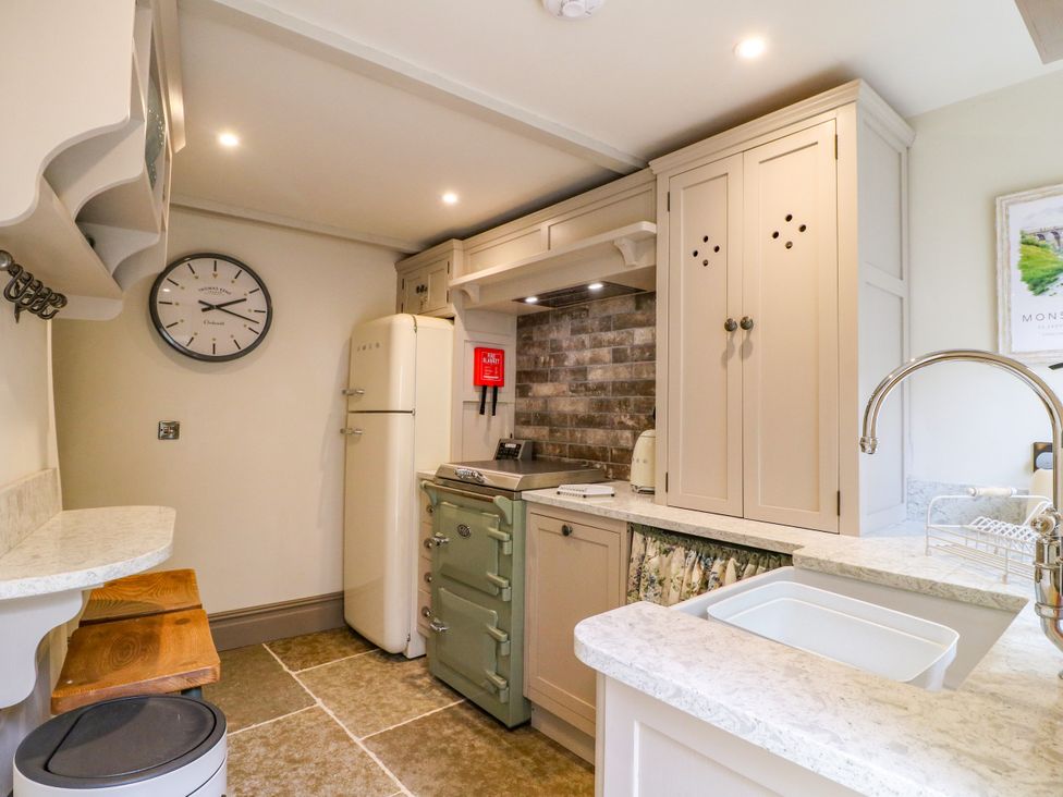 A kitchen with refrigerator, stove, sink, and cabinets at Hope Cottage Great Longstone