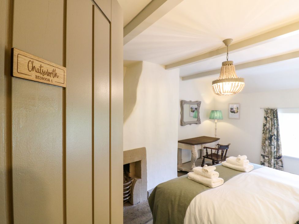 A bedroom with beds and a table at Hope Cottage in Great Longstone
