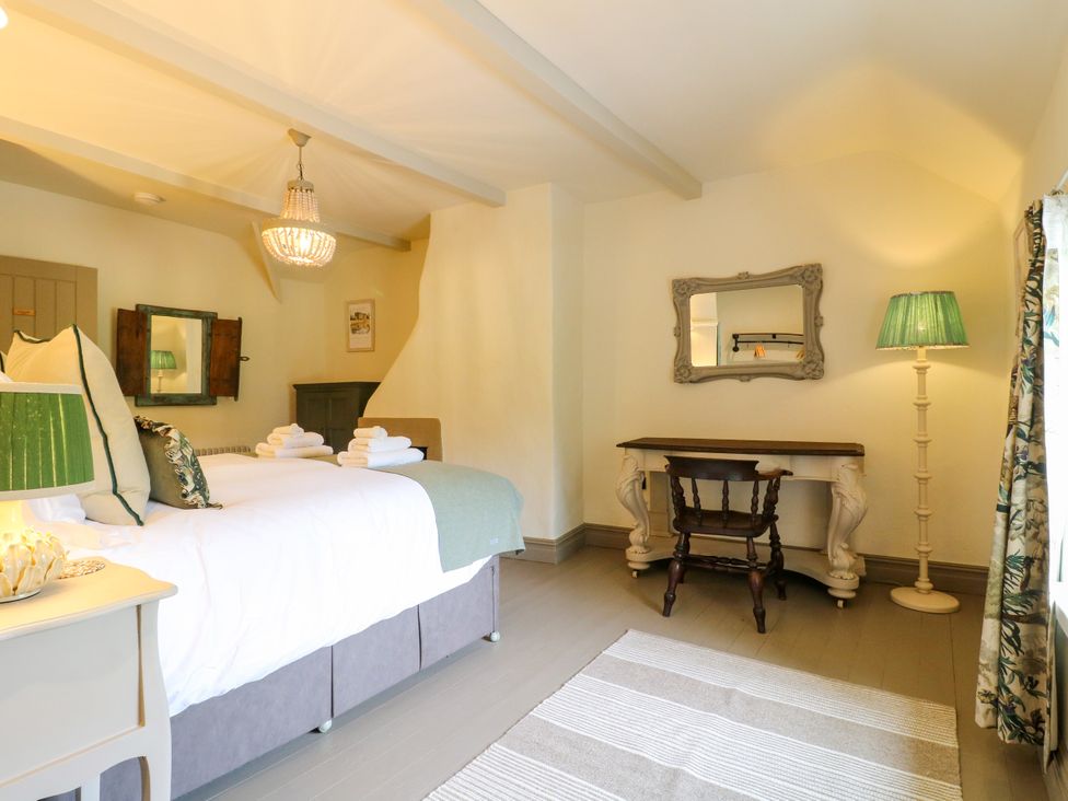 A bedroom with a bed and a table at Hope Cottage in Great Longstone