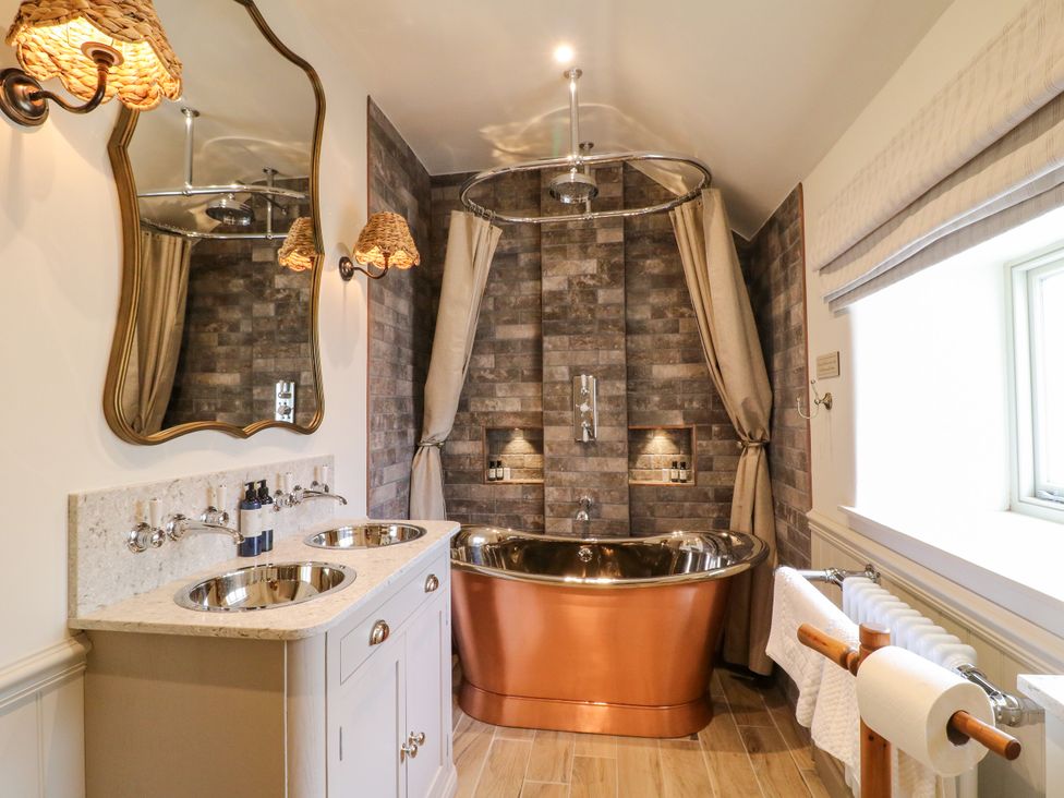 A bathroom with a copper bathtub and two washbasins at Hope Cottage in Great Longstone