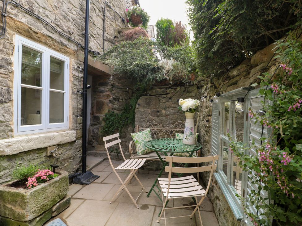 A garden with a table, chairs and planters at Hope Cottage in Great Longstone