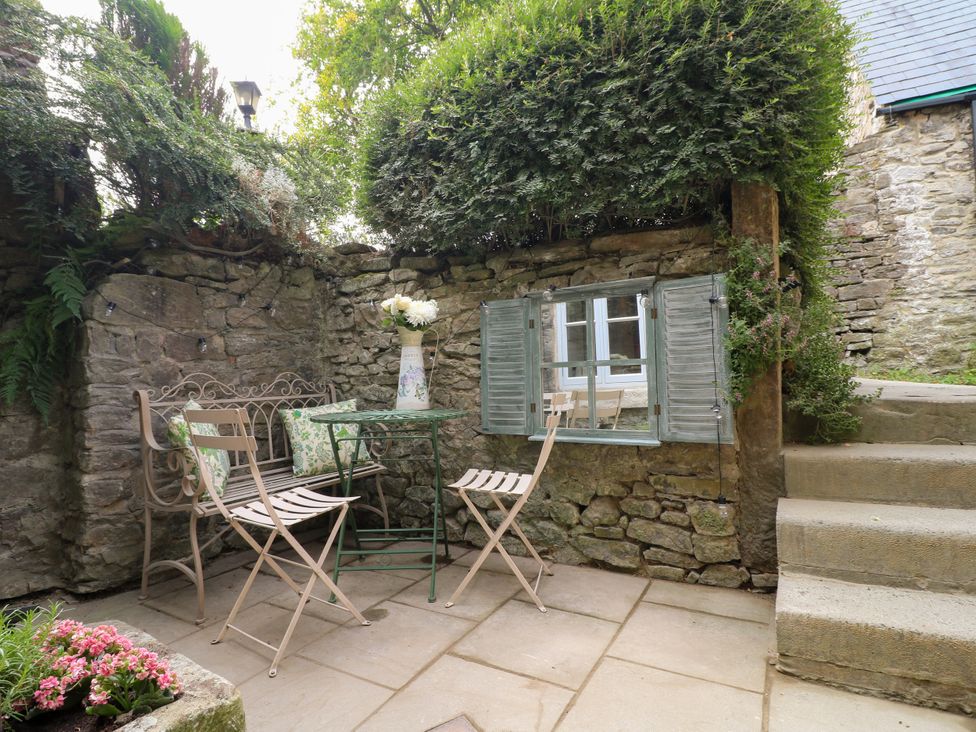 A garden area with a stone wall and furniture at Hope Cottage in Great Longstone