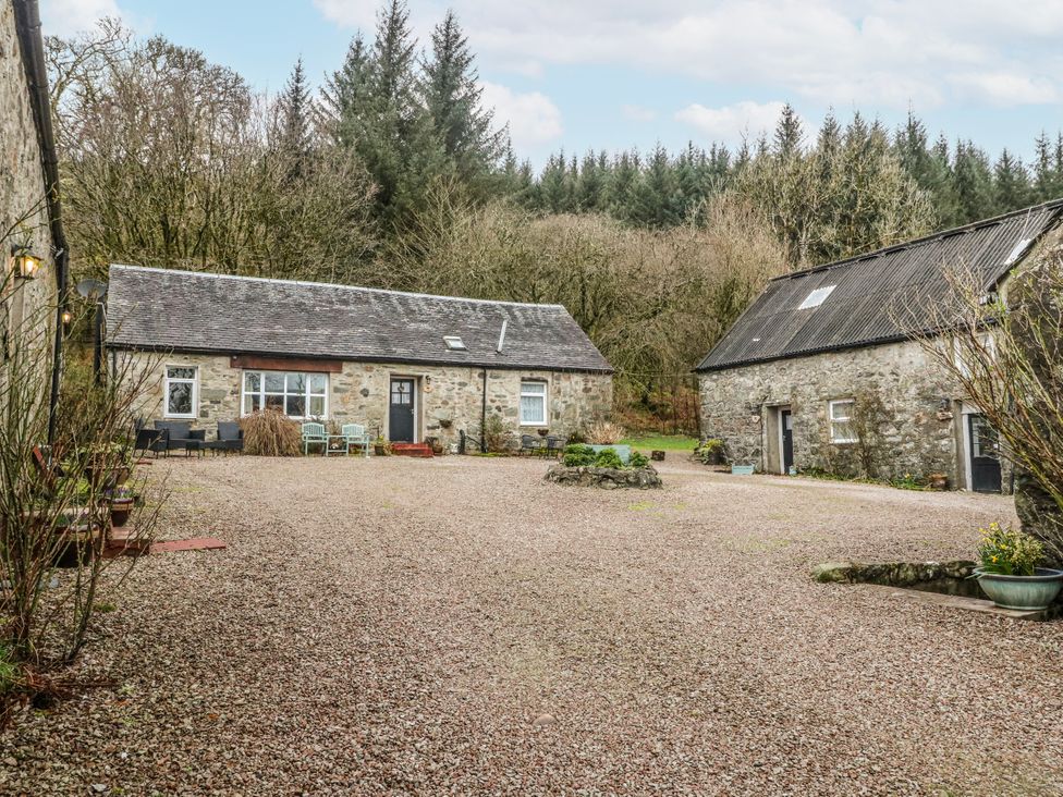 An outdoor area with two stone cottages and gravel pathway at Oak Killean Farmhouse Cottages near Inveraray