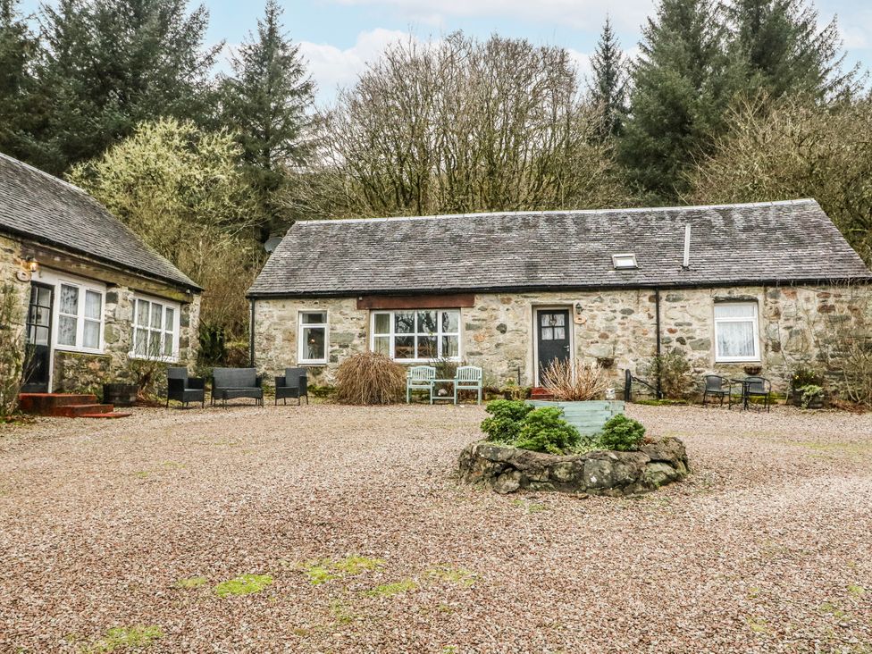 A cottage with a gravel area and chairs at Oak Killean Farmhouse Cottages near Inveraray