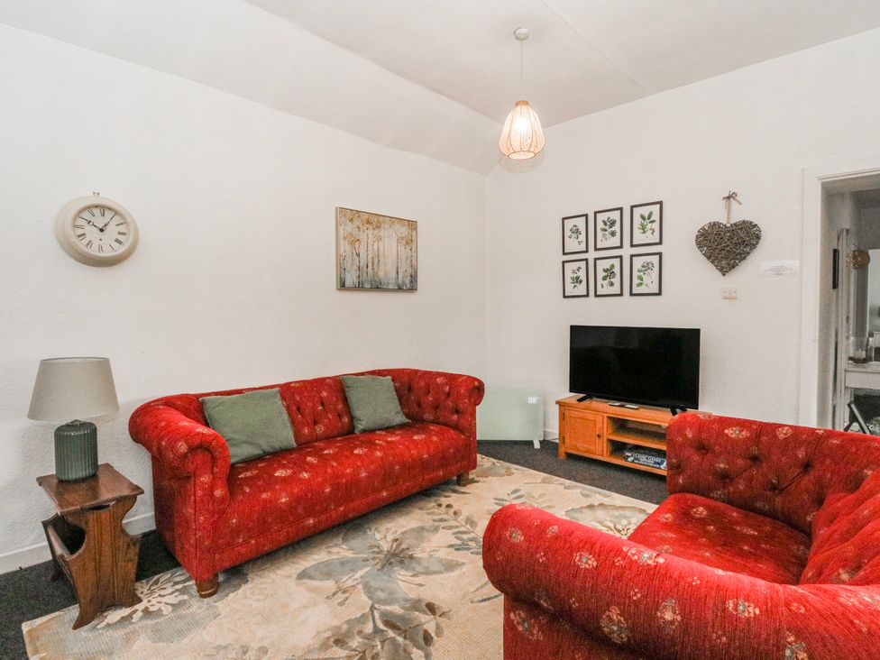 A living room with red sofas and television at Oak near Killean Farmhouse Cottages Inveraray