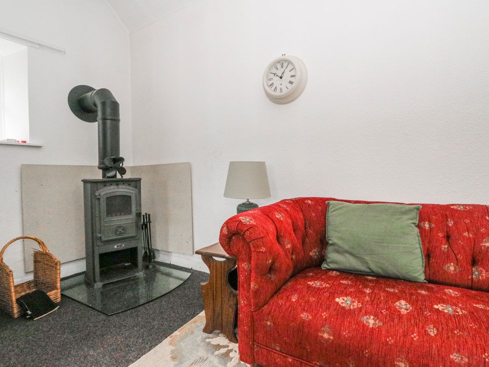 A living room with a sofa and wood stove at Oak near Killean Farmhouse Cottages in Inveraray
