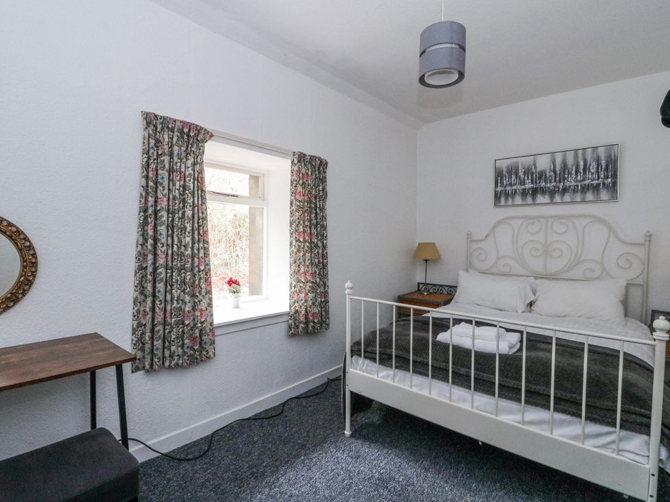 A bedroom with a bed, curtains, and a table at Oak Killean Farmhouse Cottages near Inveraray