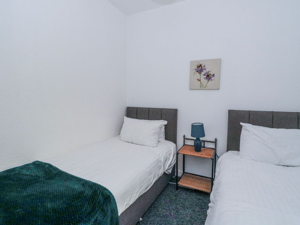 A bedroom with two beds and a nightstand in Oak near Killean Farmhouse Cottages near Inveraray