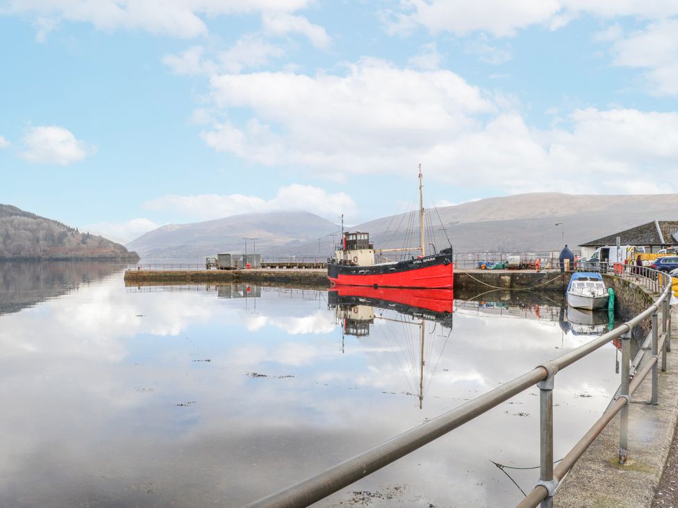 A boat at a pier reflecting on water at Oak Killean Farmhouse Cottages near Inveraray