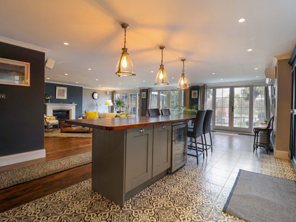 A kitchen with an island and bar stools at River Haven in Thames Ditton