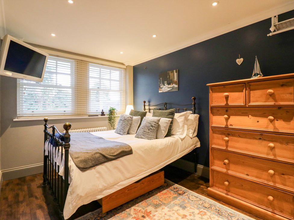 A bedroom with a bed and dresser at River Haven in Thames Ditton