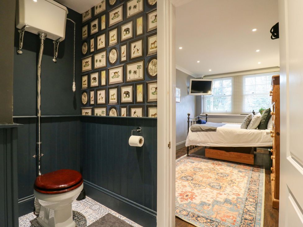 A bathroom with a toilet and a bedroom visible in the background at River Haven in Thames Ditton