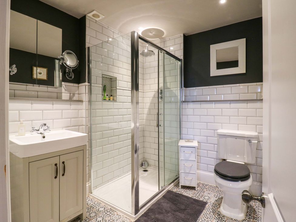 A bathroom with a shower, toilet, and sink at River Haven in Thames Ditton