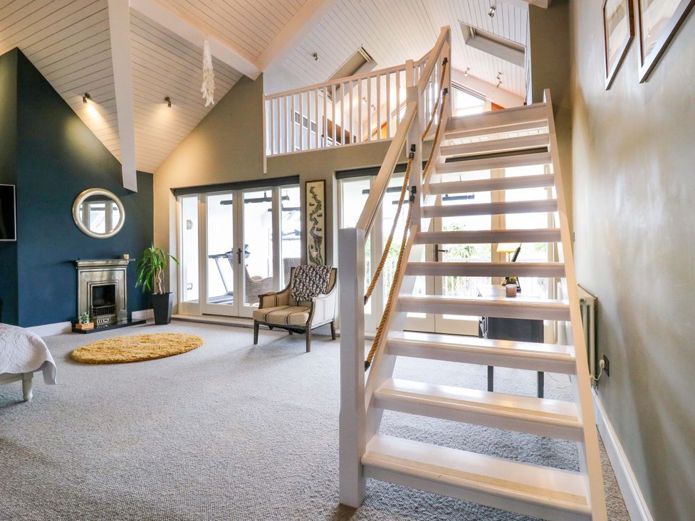 A living room with a staircase and an armchair at River Haven in Thames Ditton