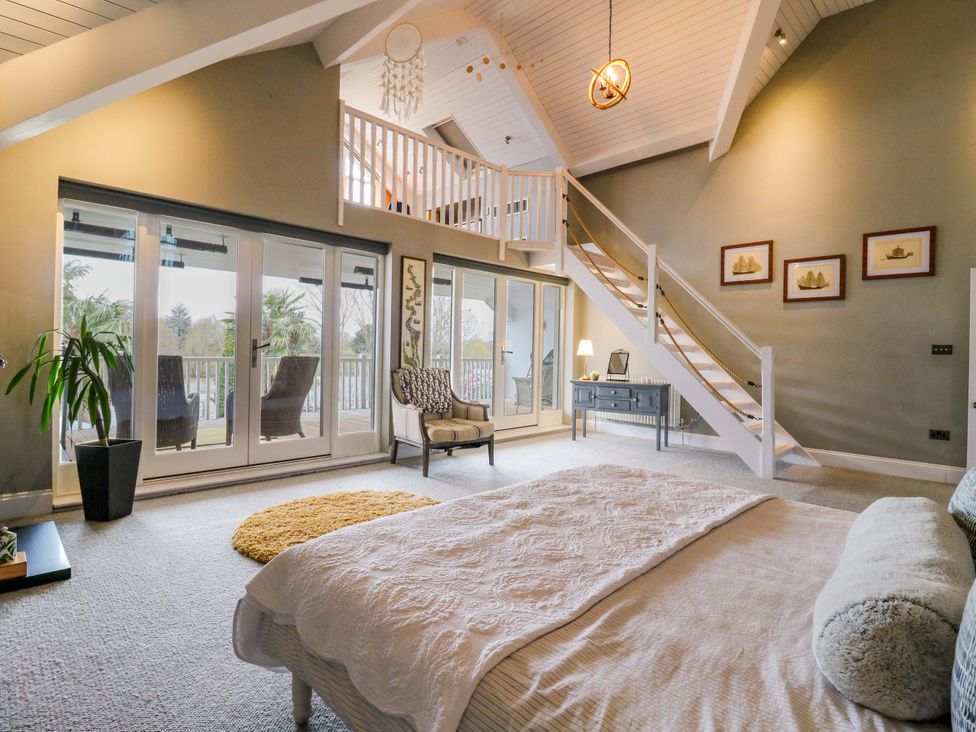 A bedroom featuring a bed, chairs, and stairs at River Haven in Thames Ditton