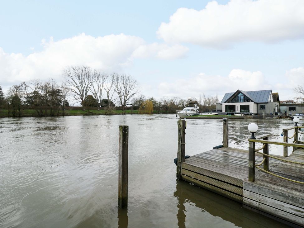 A view of a river with a house and a dock at River Haven in Thames Ditton