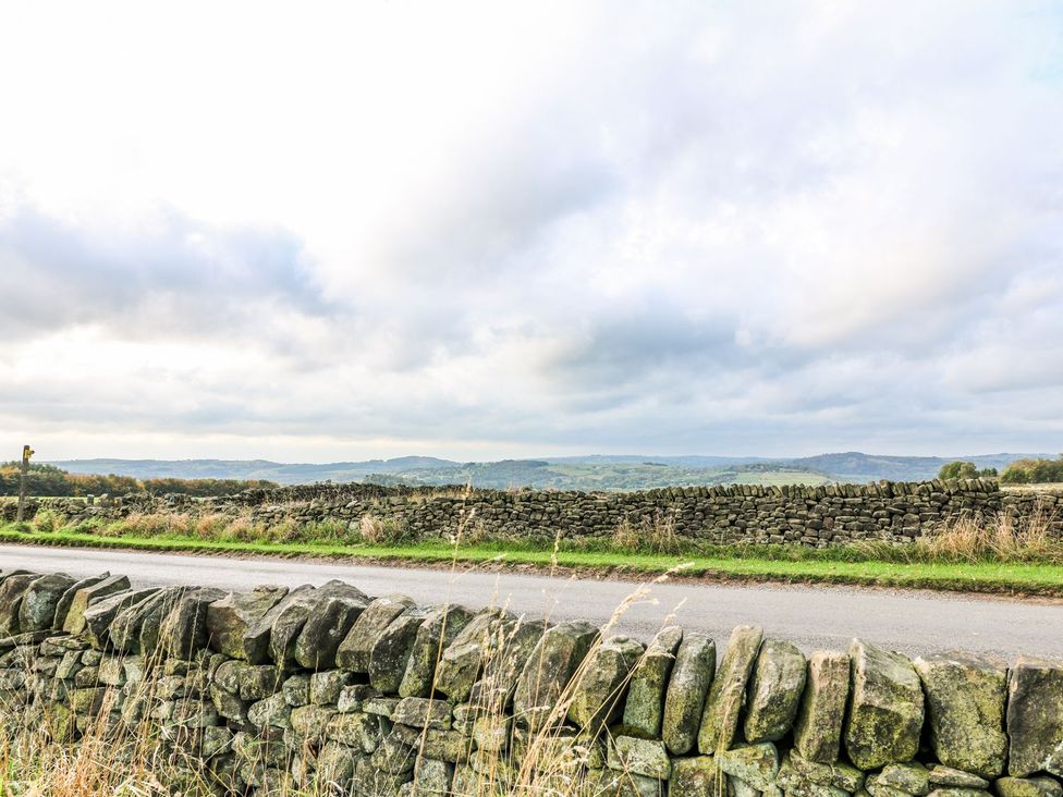 A stone wall and a road with hills in the distance at Riber View Barn Chesterfield