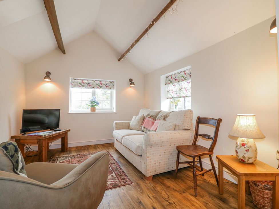 A living room with a sofa, chair, and TV at America Lodge in Oakham